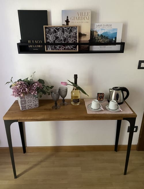 Wooden desk with black legs in Lake Como room, styled with purple flowers, kettle, and coffee cups