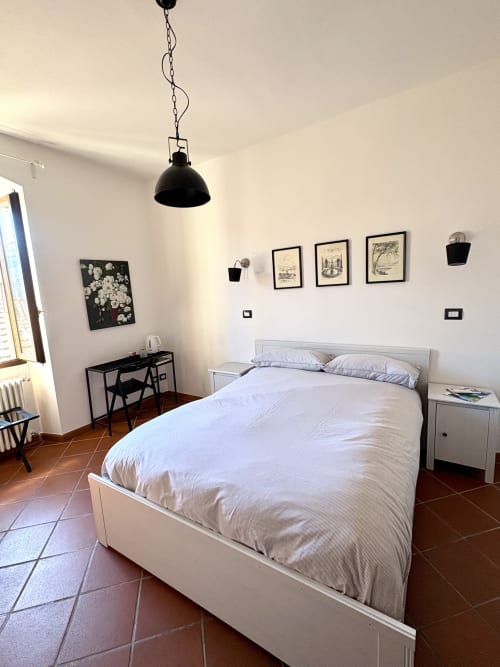 Bright bedroom at La Dolce Casa B&B in Cremia with white bed, black pendant light, desk, and framed artwork