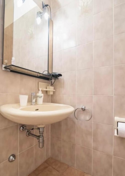 Modern bathroom with round white sink, beige tiled walls, and shower at La Dolce Casa B&B in Cremia