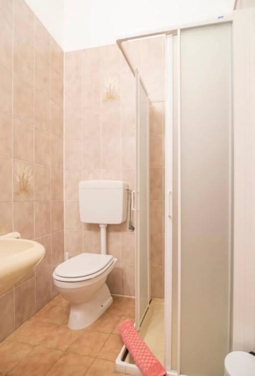 Clean bathroom with toilet, shower enclosure, and tiled walls at La Dolce Casa B&B in Cremia, Italy