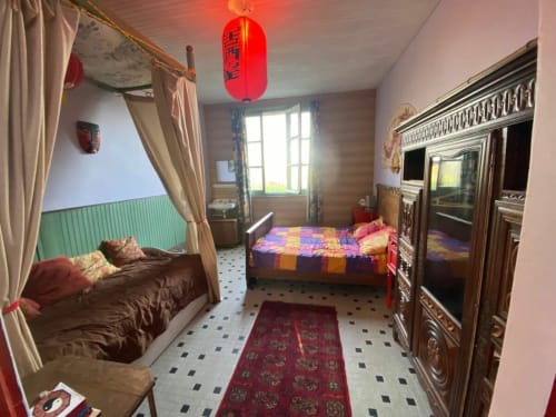 Colorful bedroom at Le Lama Zébré BnB in Penmarch with two beds and ornate wooden wardrobe