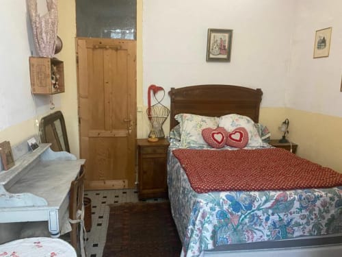 Cozy bedroom at Le Lama Zébré B&B in Penmarch with wooden furniture, floral bedding, and heart-shaped pillows