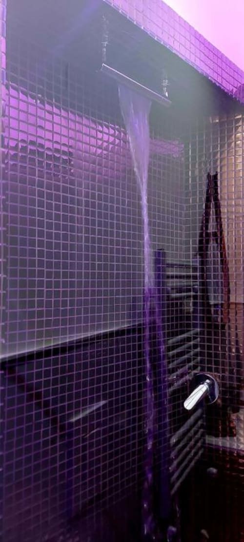 Modern purple tiled bathroom with glass shower enclosure at Pignasecca Domus, Naples