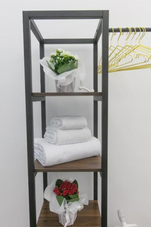 Dark shelving unit at Pignasecca Domus Naples with white towels, flowers, and toiletries
