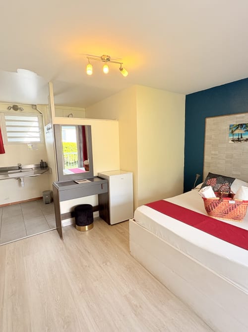 Chambre double Hôtel le soleil couchant avec lit, coiffeuse, kitchenette et accès à la terrasse avec vue sur le jardin