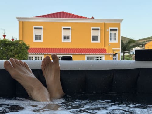 Person relaxing in pool at Golden Mermaid Villa, a yellow beachfront Portuguese B&B with red roof
