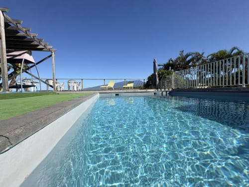Piscine scintillante de l'Hôtel le soleil couchant à St Pierre, La Réunion, avec vue sur les montagnes et transats