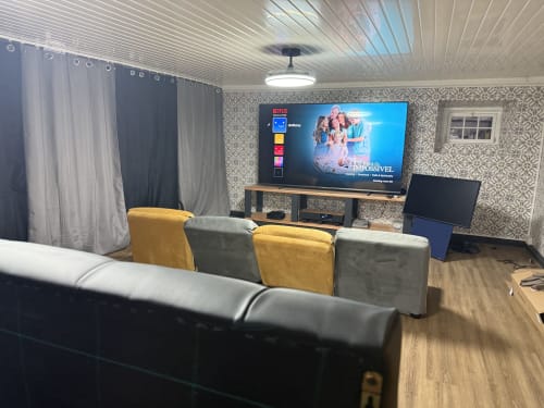 Golden Mermaid Villa media room with Netflix display, yellow and gray seating, wood flooring, and patterned wallpaper