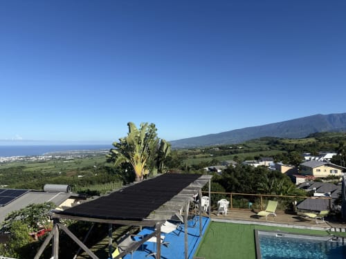 Terrasse de l'Hôtel le Soleil Couchant avec piscine, palmier et vue sur l'océan à Saint-Pierre, La Réunion