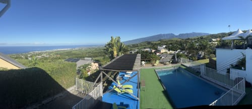 Hôtel le soleil couchant à Saint-Pierre, Réunion : vue aérienne de la piscine, pelouse soignée et littoral océanique avec montagnes