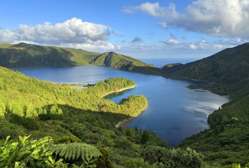 Scenic twin lakes surrounded by lush green mountains and forests under blue sky with clouds