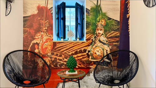 Due sedie nere intrecciate rivolte verso un'opera d'arte ornamentale e finestra blu presso l'hotel Location 10 Agency a Palermo