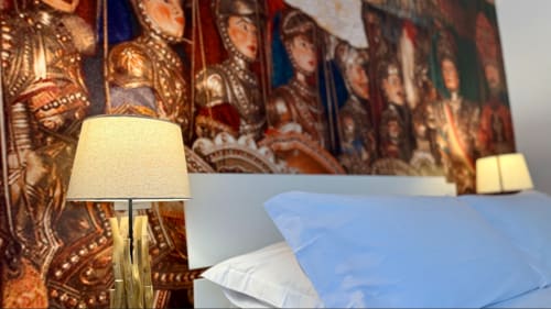 Lussuosa camera d'hotel a Palermo con testata ornamentale, lampada crema e cuscini blu presso Location 10 Agency