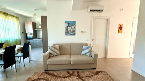 Soggiorno moderno in appartamento a Palermo con divano beige, cuscini rigati e cucina a vista