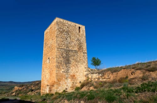 Ruinas de antigua torre de piedra en Castillo de Locubín con paisaje árido y cielo azul despejado