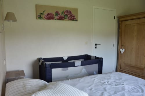 Chambre douillette à La Clef des Bois avec lit double, lit parapluie et décoration murale florale