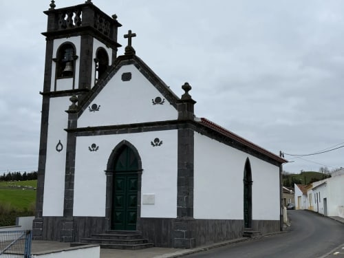 Capela histórica branca e preta com campanário em aldeia portuguesa próxima à Vila Sereia Dourada