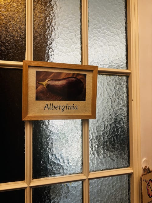 Wooden frame displaying eggplant photo with 'Albergínia' text, hung on textured wall at Mas Ribas Hotel in Palamos