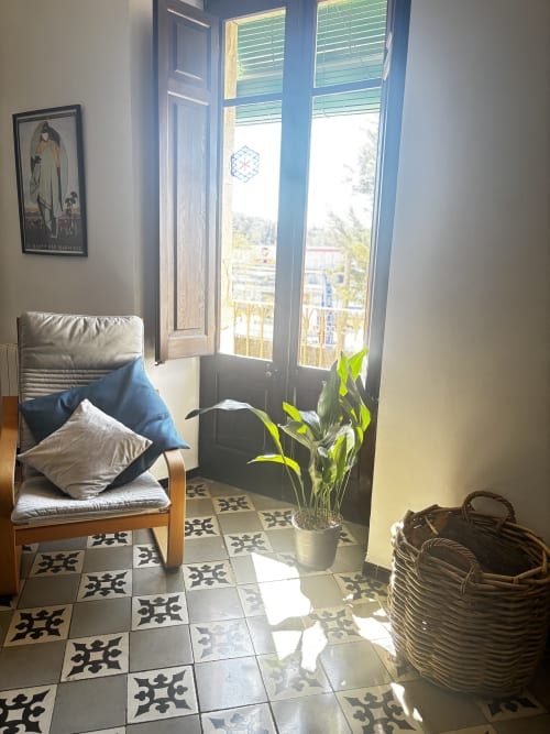 Bright room at Mas Ribas Hotel Palamos with wooden chair, potted plant, patterned tiles, and garden view balcony doors