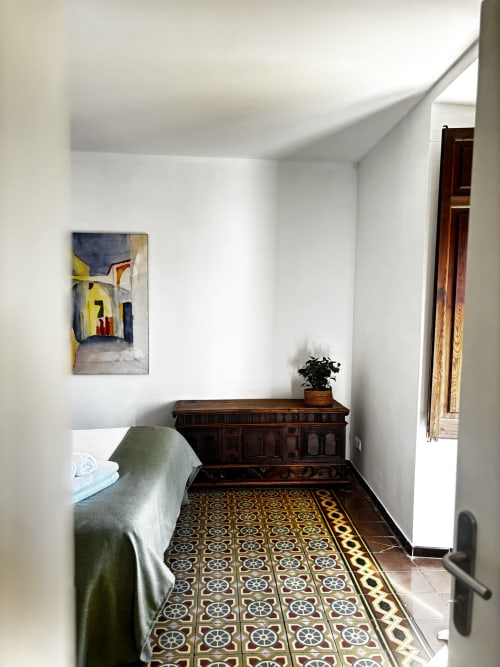 Cozy bedroom at Mas Ribas Hotel in Palamós with green blanket, dark wooden dresser, and decorative patterned tile floor