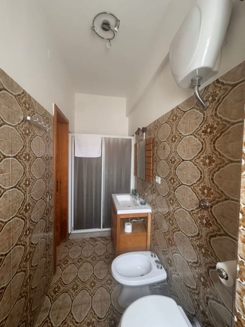 Baño moderno en B&B Residenza Leonardo en Falconara Marittima con paredes alicatadas, inodoro, lavabo y plato de ducha