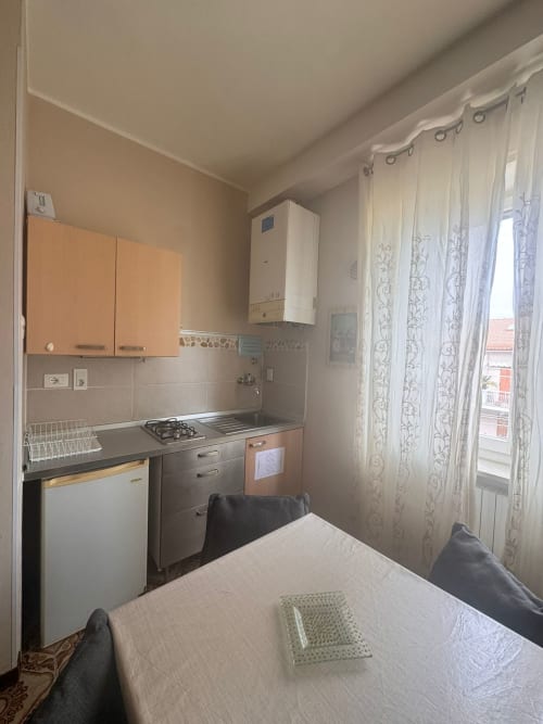 Cocina compacta con muebles color beige, estufa de gas y ventana con vistas a Falconara Marittima en B&B Residenza Leonardo