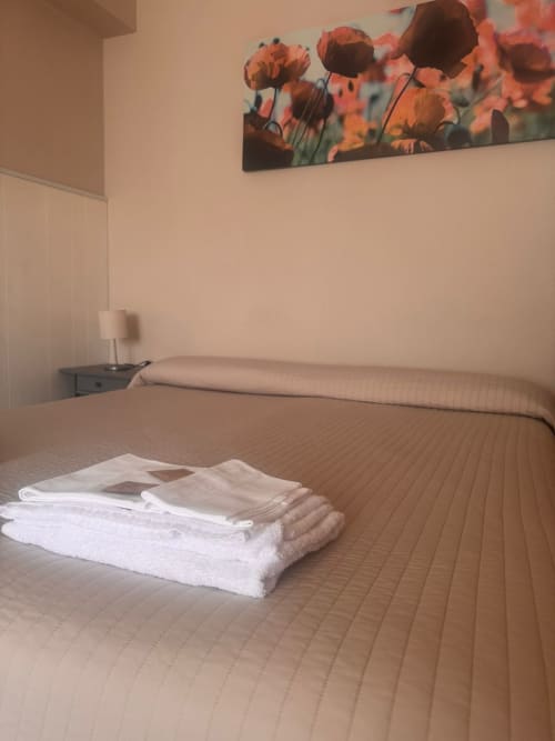 Dormitorio con toallas blancas en la cama, cuadros de amapolas, lámpara de mesita y vistas al mar en B&B Residenza Leonardo, Falconara