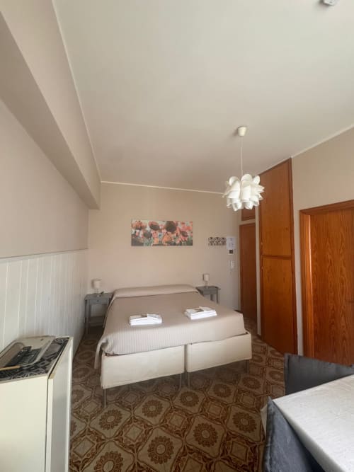 Habitación luminosa con cama doble, lámpara colgante blanca, puertas de madera y piso estampado en B&B Residenza Leonardo, Falconara
