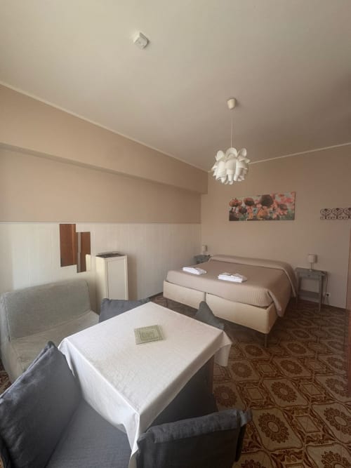 Amplia habitación doble en B&B Residenza Leonardo, Falconara Marittima con camas, sofá, lámpara colgante y suelos con estampados