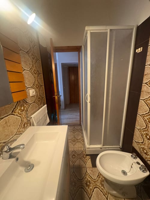 Baño en B&B Residenza Leonardo, Falconara Marittima con lavamanos blanco, inodoro, bidé, ducha y azulejos con patrón