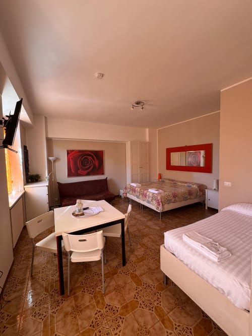 Camera familiare in B&B Residenza Leonardo a Falconara Marittima con letti, scrivania, angolo cottura e quadri di rose rosse