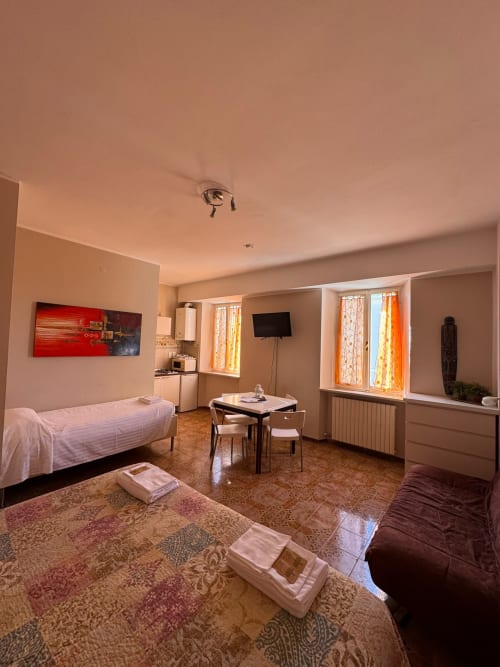 Amplia habitación familiar en B&B Residenza Leonardo en Falconara Marittima con dos camas, cocina americana, mesa de comedor y TV