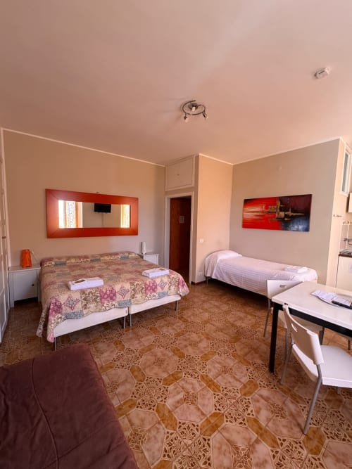 Habitación familiar en B&B Residenza Leonardo en Falconara Marittima con dos camas, espejo rojo, cocina y piso de terracota