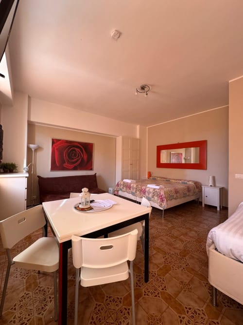 Espacioso estudio en B&B Residenza Leonardo, Falconara Marittima, con mesa de comedor, cama, sofá y comodidades modernas