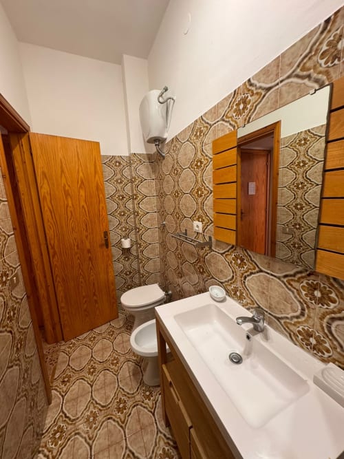Baño en B&B Residenza Leonardo, Falconara Marittima con azulejos decorativos, lavabo blanco, inodoro y puertas de madera