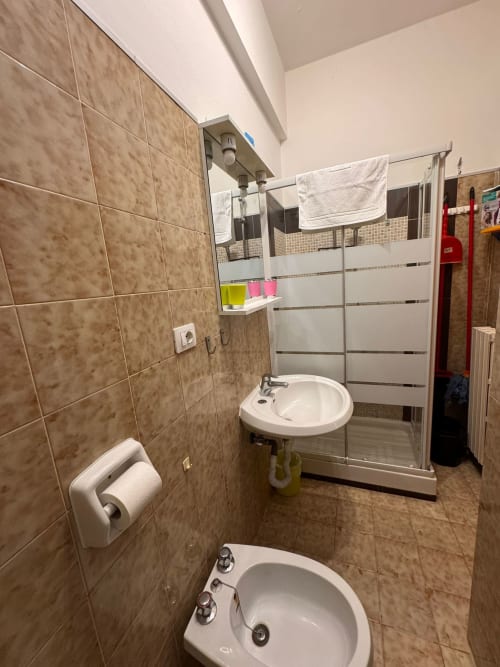 Baño moderno con paredes de azulejos marrones, bidé, lavabo redondo y ducha con mampara de cristal en B&B Residenza Leonardo, Falconara