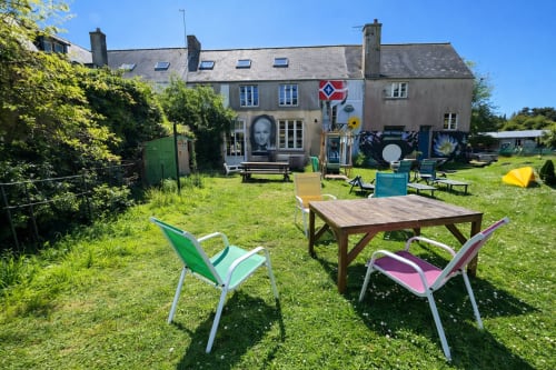 Colorful outdoor seating area at Le Lama Zébré guesthouse in Penmarch with picnic tables and chairs