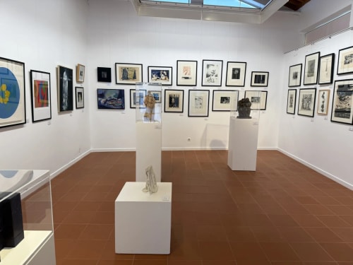 Art gallery exhibition room with framed drawings and sculptures on pedestals at Golden Mermaid Villa