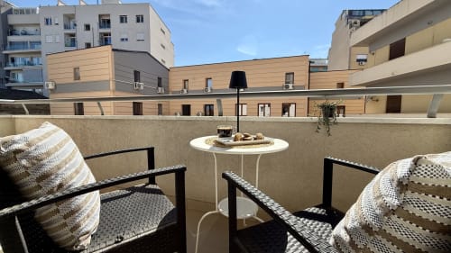 Terrazza moderna con sedie nere, tavolino bianco e cuscini a righe affacciati sul cortile residenziale di Palermo