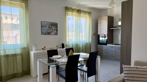Moderno appartamento a Palermo con 2 camere, zona living, cucina e vista sulla città attraverso tende verdi