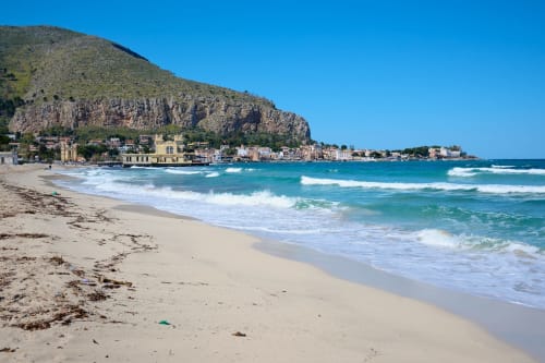 Spiaggia di Mondello a Palermo con acque turchesi, costa sabbiosa ed edifici colorati ai piedi di spettacolari scogliere rocciose