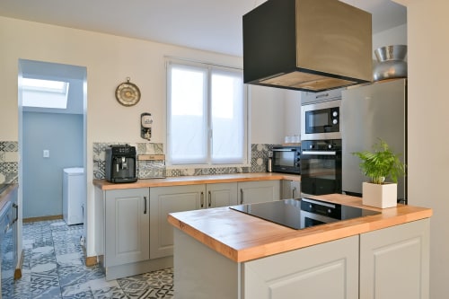 Moderne Küche im Hotel Ziane in der Normandie mit Holzarbeitsplatten, cremefarbenen Schränken und Edelstahlgeräten