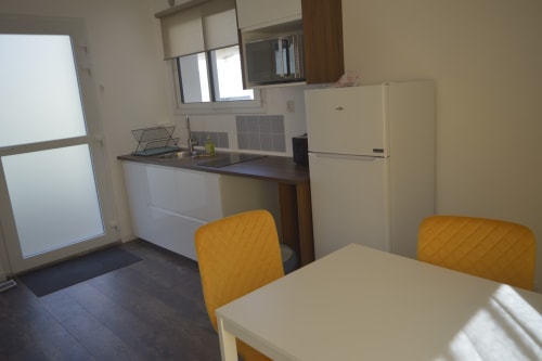 Cuisine moderne et coin repas de la résidence avec électroménagers blancs et chaises jaunes à Landéda