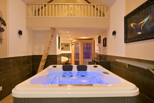 Luxe bubbelbad met blauwe verlichting in hotel Ziane in Normandië, voorzien van twee hoofdsteunen en moderne spa-voorzieningen