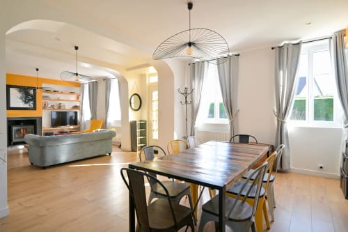 Moderner offener Essbereich des Hotels Ziane in der Normandie mit Holztisch, zeitgenössischer Beleuchtung und Kamin