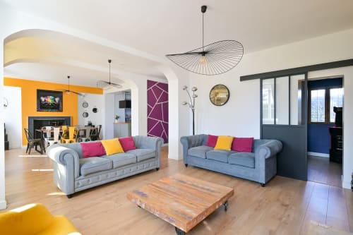 Modernes offenes Wohnzimmer des Hotels Ziane mit grauen Chesterfield-Sofas, bunten Kissen, Holzboden und zeitgenössischem Design
