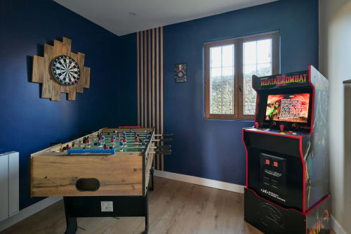 Spielzimmer des Hotels Ziane mit Kickertisch, Mortal Kombat Arcade, Dartscheibe und blauen Wänden in der Normandie