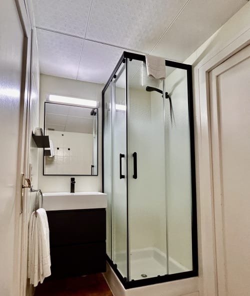 Modern bathroom at Hostal Estació in Puigcerdà with shower enclosure, black vanity, and mirror