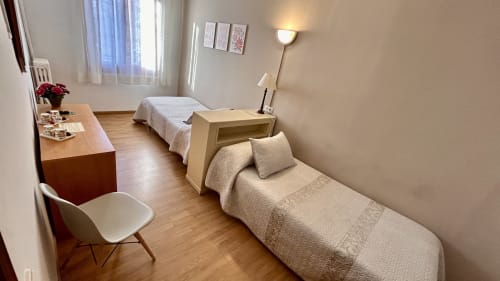 Quad room at Hostal Estació in Puigcerdà with two beds, desk, wooden floor, and mountain views