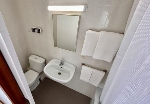 Clean bathroom at Hostal Estació in Puigcerdà with toilet, sink, mirror, towel rails and shower area